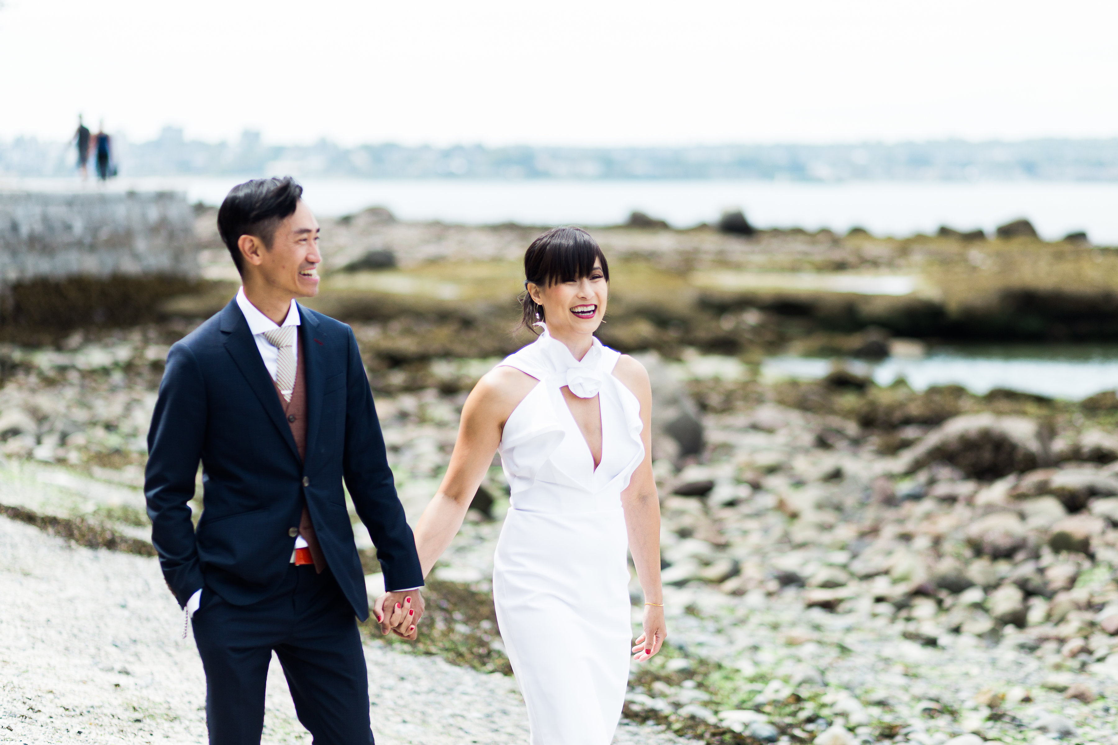 Bride and groom holding hands and smiling as they walk the Vancouver Seawall