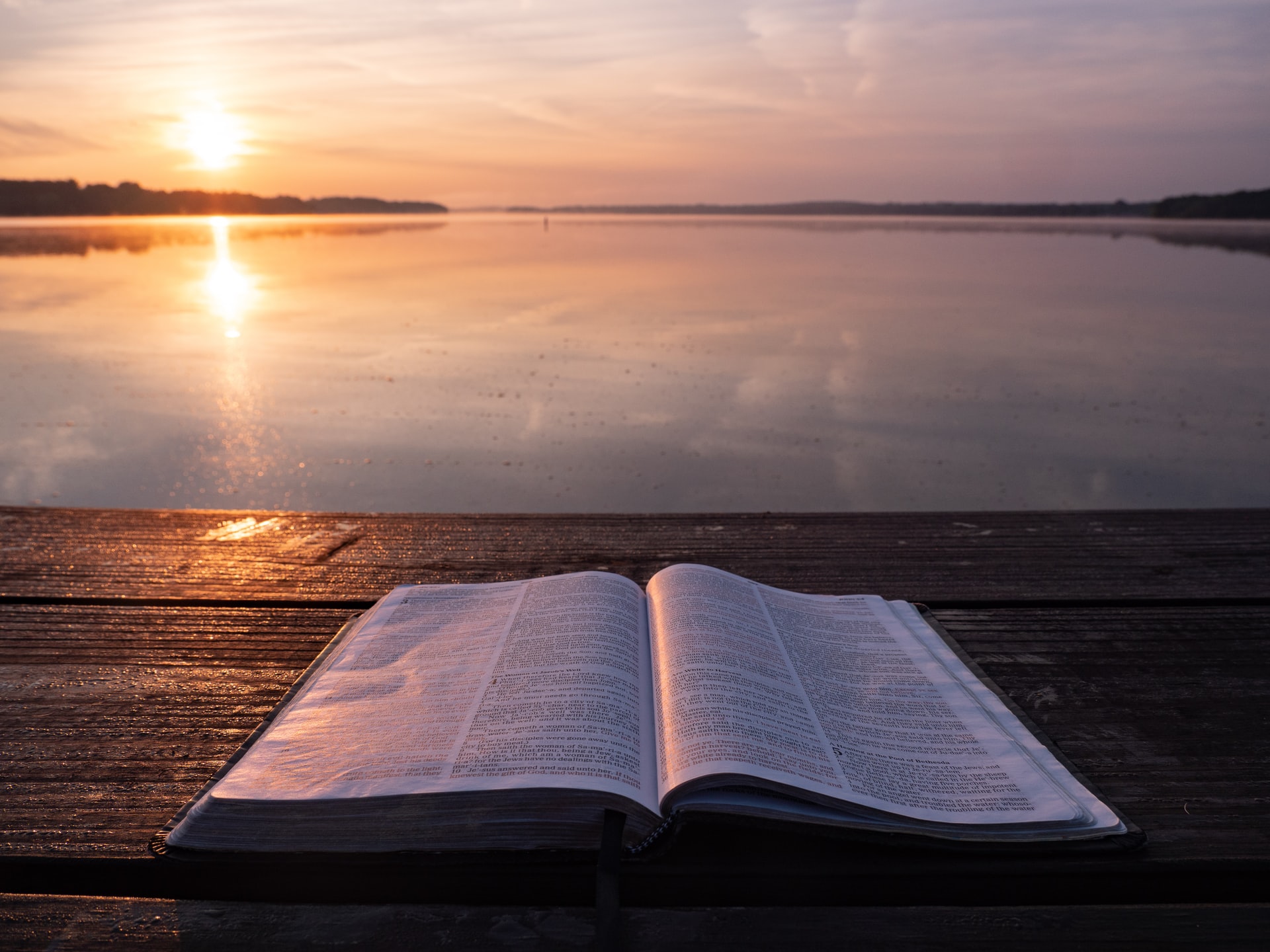 bible on dock overlooking the water and sunset