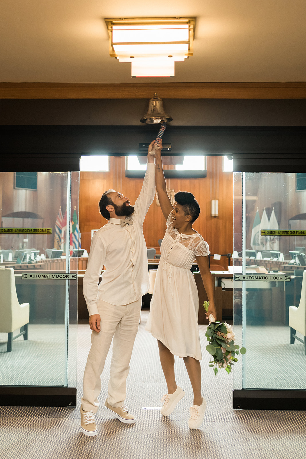 newlyweds ringing the bell at Vancouver City Hall after a Young Hip & Married elopement