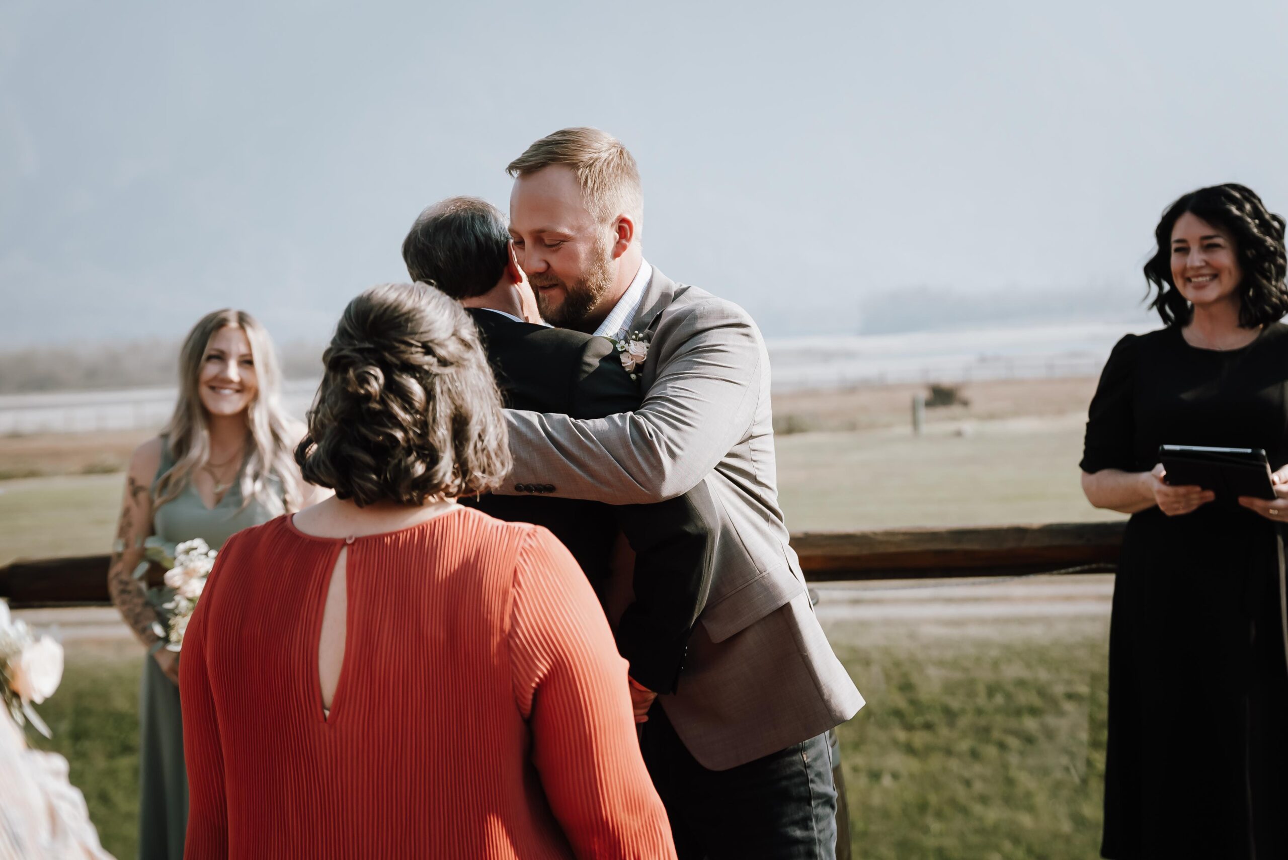 groom hugging parents at end of the aisle, wedding party processional