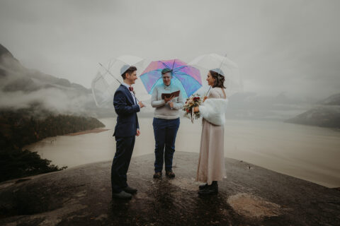 Young Hip & Married French speaking wedding officiant Beth officiating an elopement in the rain with a couple under umbrellas