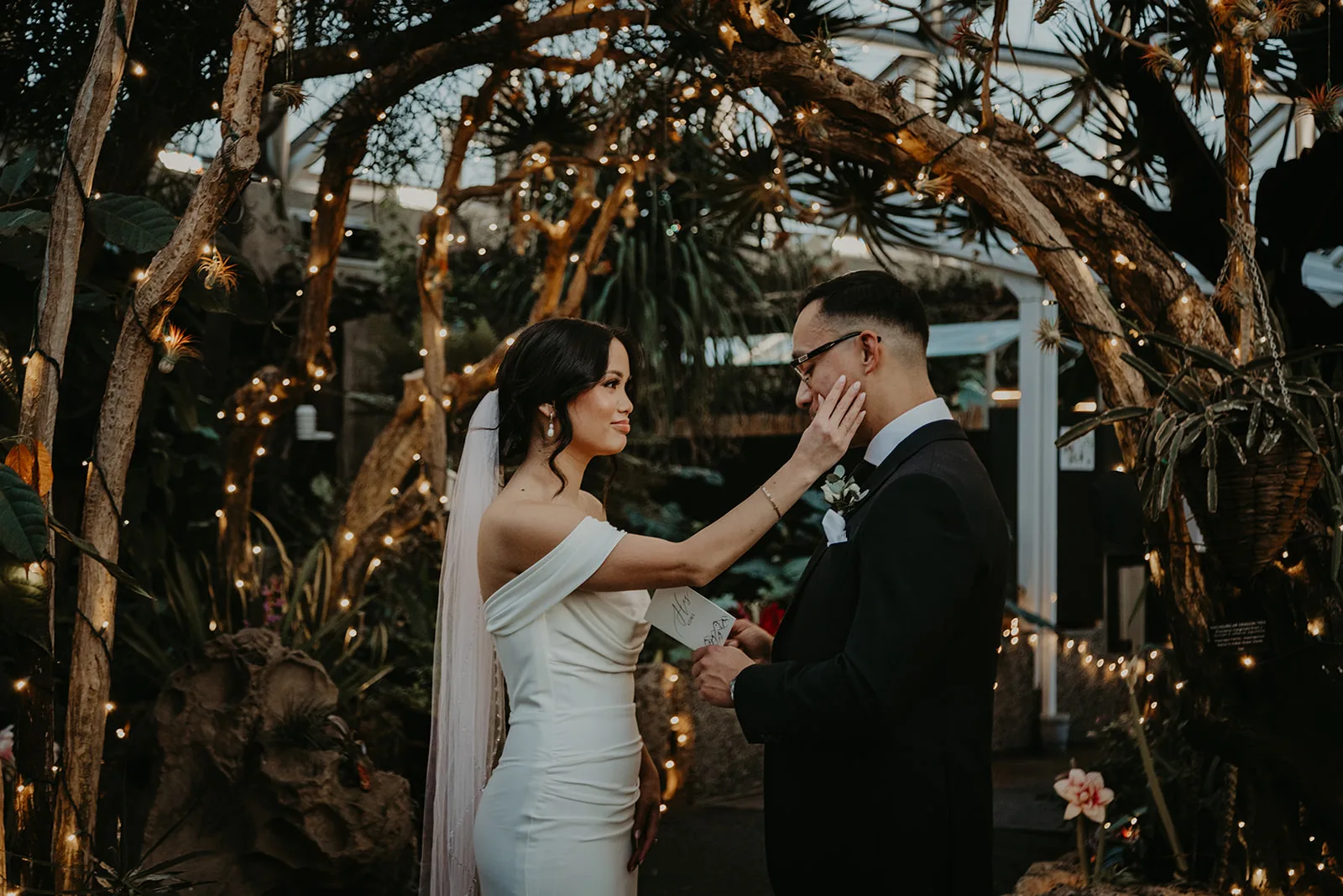Couple exchanging vows, bride wipes tears from husband's eyes