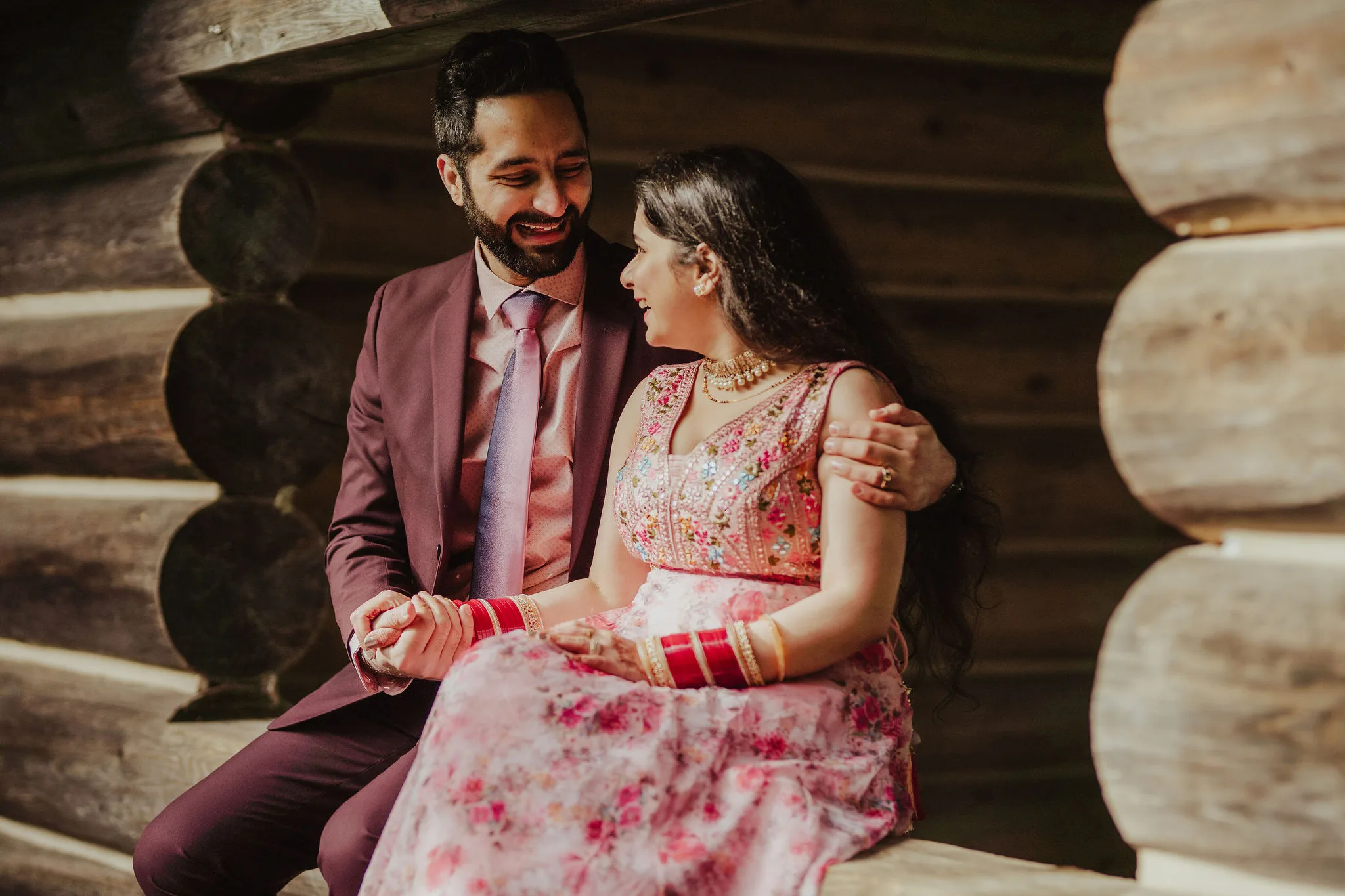 Bride and groom sit together on a windowsill holding hands